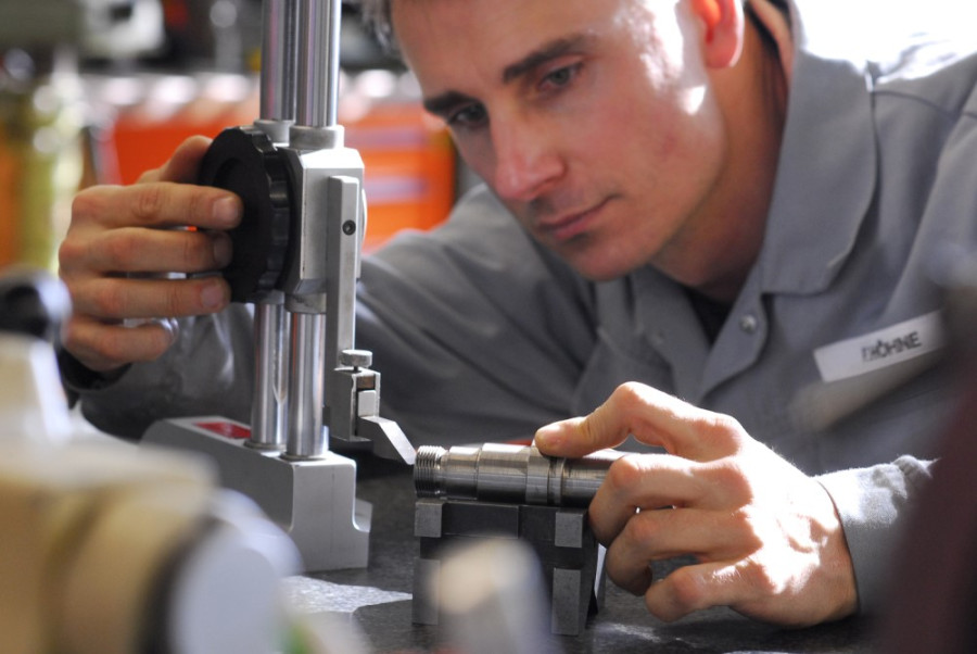 Ensuring compliance with laws and regulations, a worker examines a machine part using precise measuring equipment