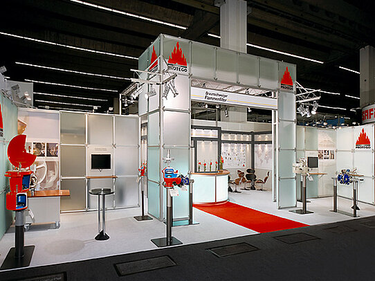 Trade show booth with PROTEGO branding, industrial valves on display, and a red carpet aisle.