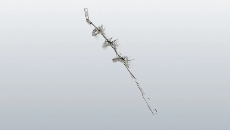 Une brosse métallique torsadée, avec plusieurs touffes de poils gris et des languettes de fixation plates aux deux extrémités, sur fond blanc.