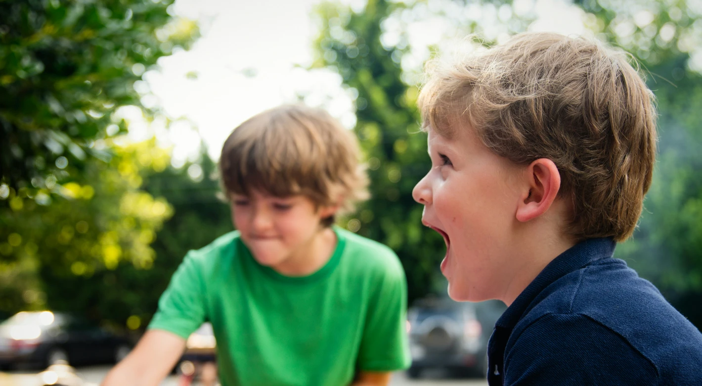 Dos niños juegan en una pequeña piscina hinchable rosa al aire libre; en primer plano se ve a uno de ellos riéndose.