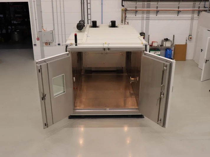 Offene industrielle Testkammer mit Doppeltüren, die den Blick auf einen Innenraum aus Edelstahl in einer sauberen Fabrik- oder Laborhalle freigibt.