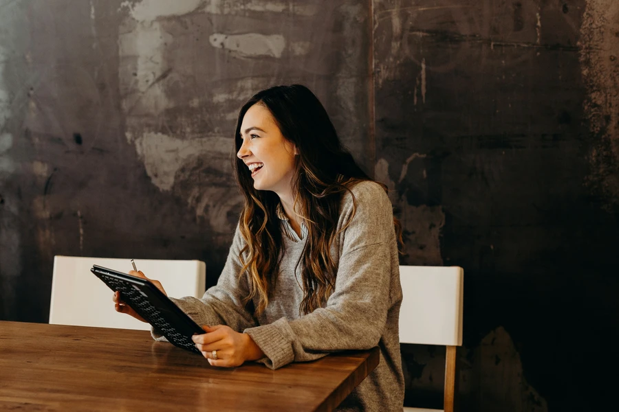A person sits at a table, engaged in work with a tablet, suggesting focus and productivity in a casual setting.
